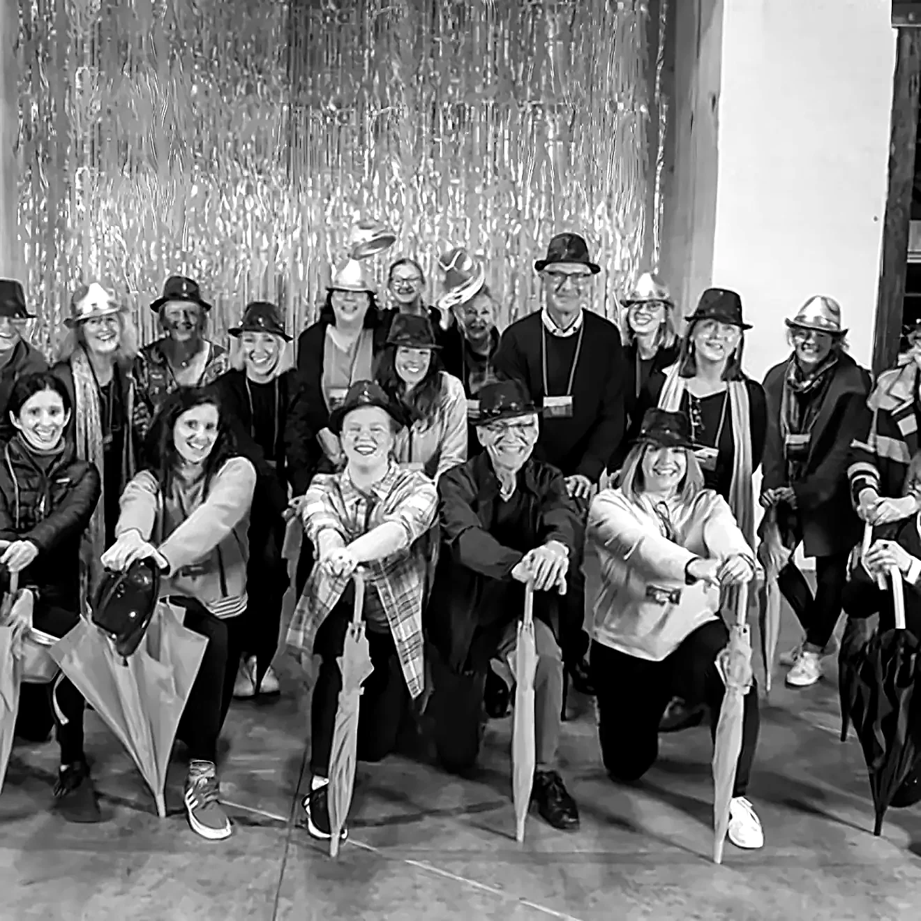 A corporate team in hats, holding umbrellas, posing after their final performance