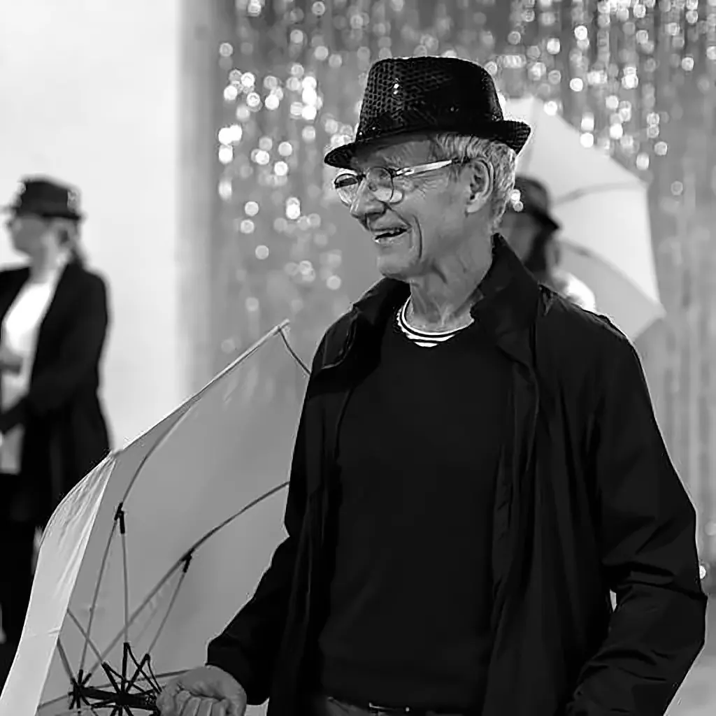 A smiling participant in a sequinned hat holding an umbrella