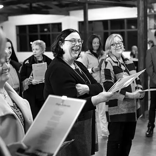 Participants laughing while learning a song from lyric sheets