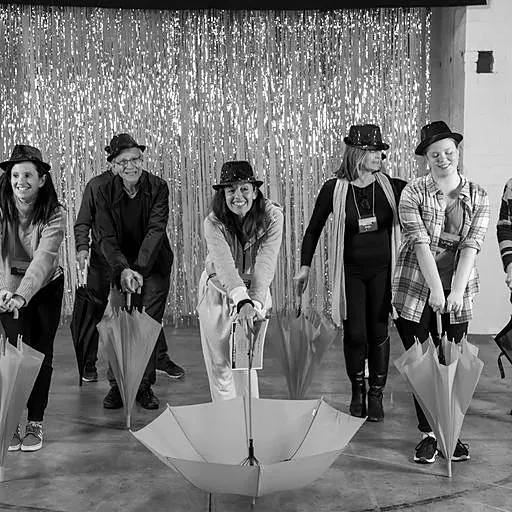 A team performing a routine with umbrellas in front of a tinsel curtain